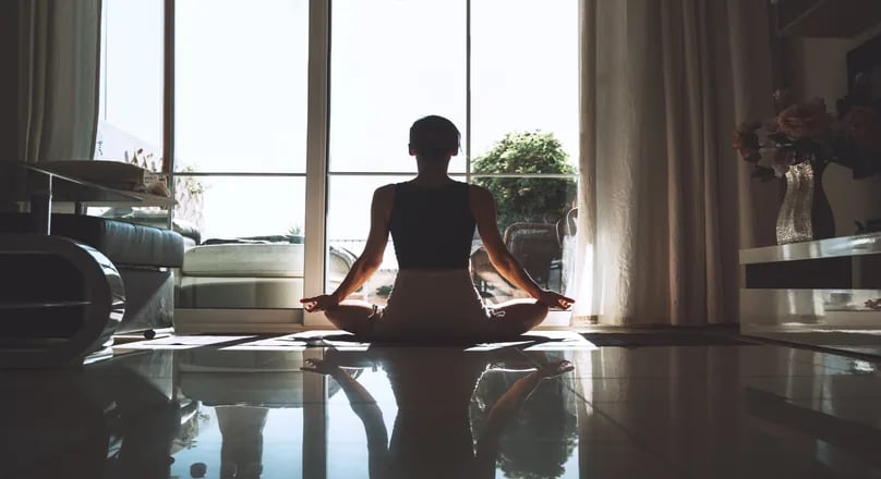 Silhouette meditating by a bright window